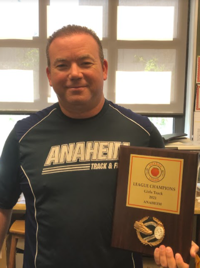 Coach Storm holding the Track and Field league champion award.