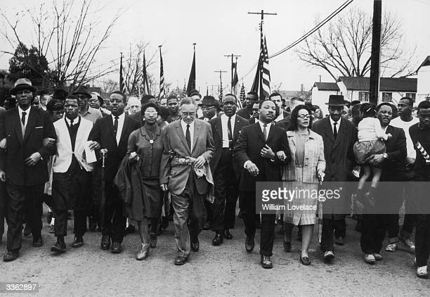 March 1965:  American civil rights campaigner Martin Luther King (1929  - 1968) and his wife Coretta Scott King lead a black voting rights march from Selma, Alabama, to the state capital in Montgomery;  among those pictured are, front row, politician and civil rights activist John Lewis (1940 – 2020), Reverend Ralph Abernathy (1926 - 1990), Ruth Harris Bunche (1906 - 1988), Nobel Prize-winning political scientist and diplomat Ralph Bunche (1904 - 1971), activist Hosea Williams (1926 – 2000 right carrying child). (Photo by William Lovelace/Daily Express/Hulton Archive/Getty Images)