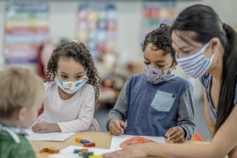 Children wearing masks while coloring in school. 